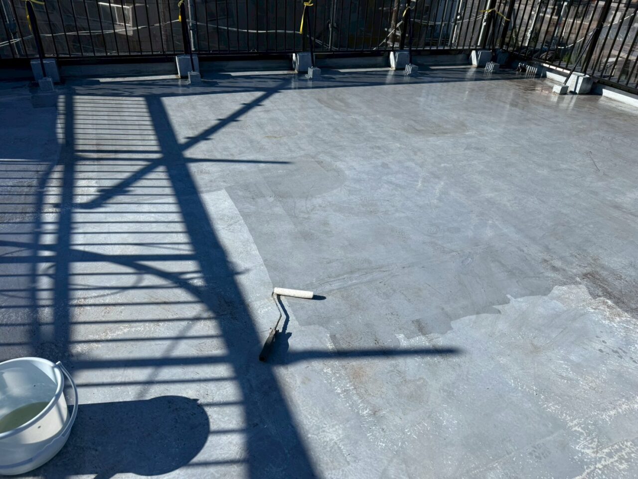 下地処理後の屋上へ防水材を塗布している様子