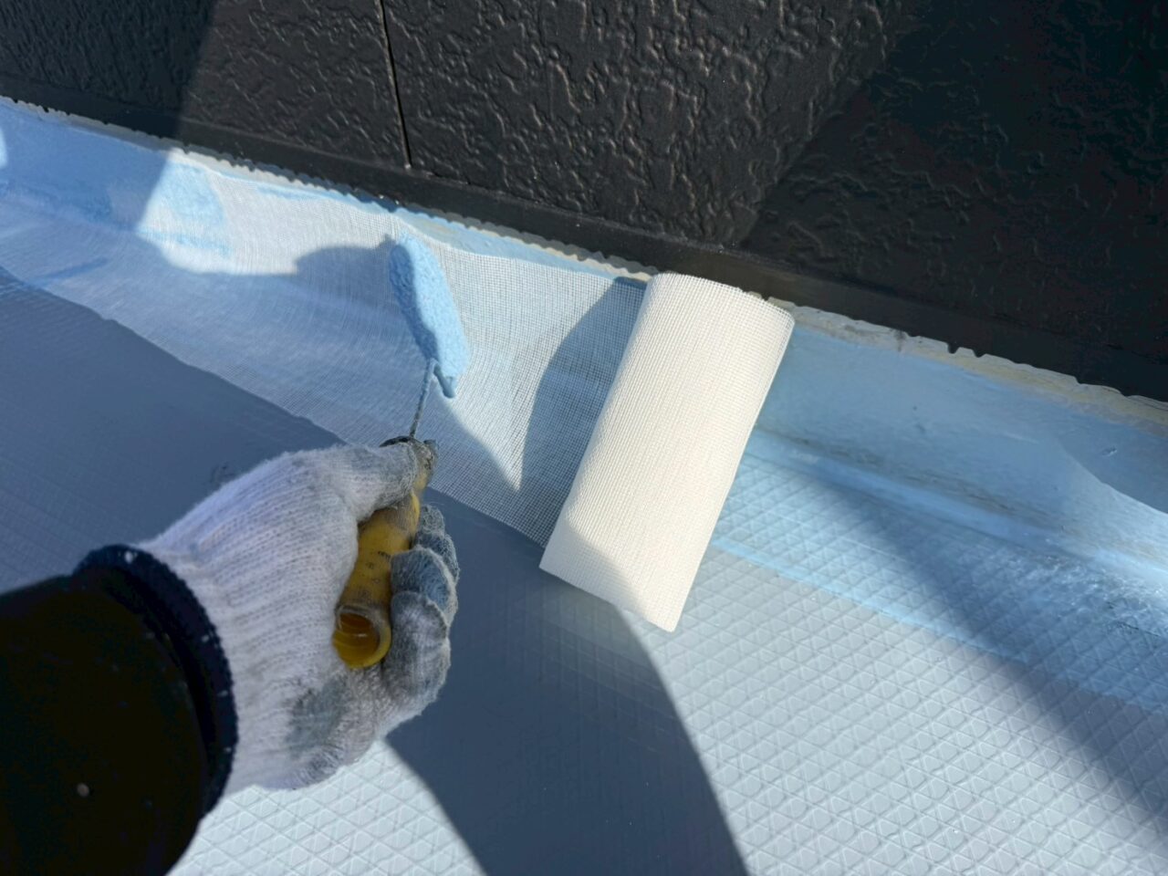 立ち上がり部分に通気緩衝シートを丁寧に貼り付ける作業