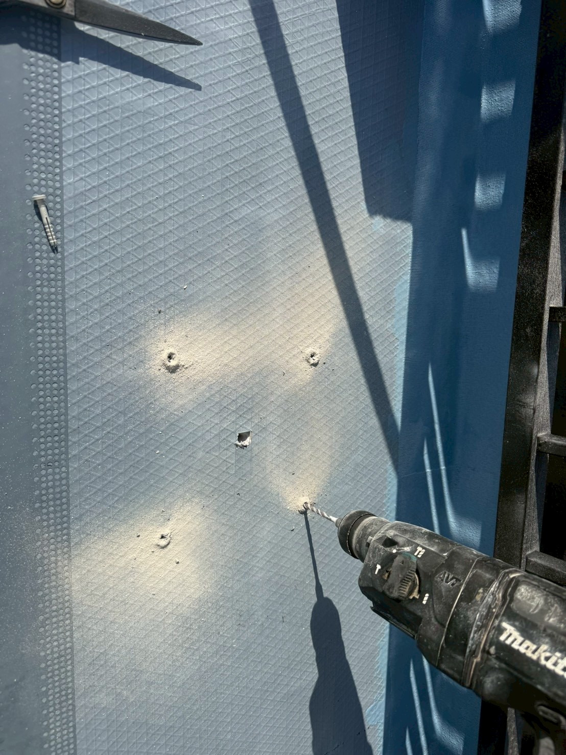 ドレン位置にドリルで穴を開けて脱気筒の設置準備をしている様子