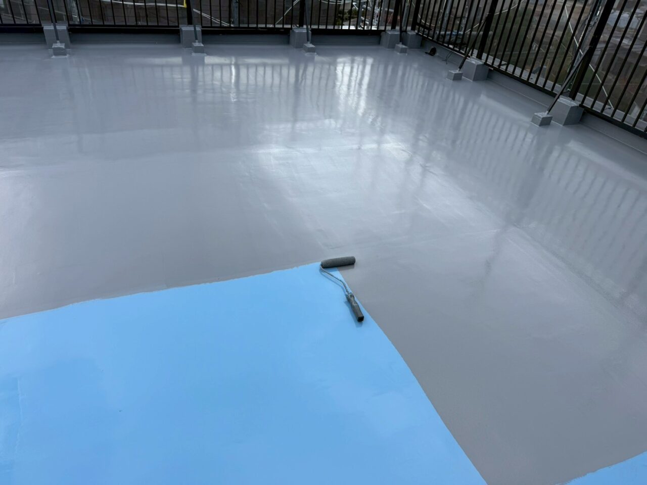 屋上防水工事で青色ウレタンを均一に塗布する工程の様子（池田市・通気緩衝工法）
